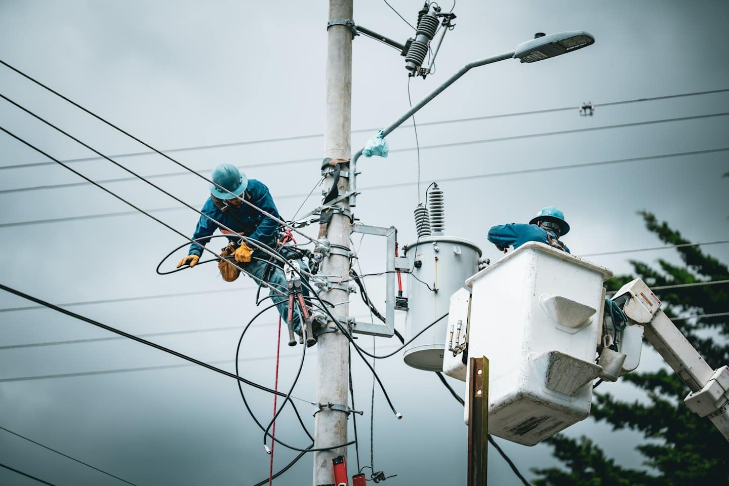 Trafo ile elektrik direğinde işçiler.