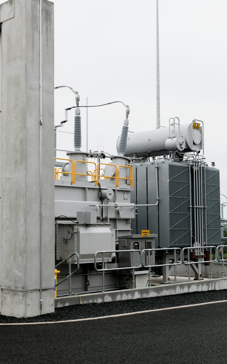 Dışarıda sarı güvenlik korkuluklu endüstriyel elektrik trafosu.